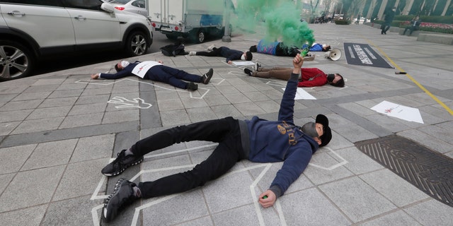 South Korean peace activists lie on a street to pay tribute to the victims of the recent protests in Burma, during a rally against Burma's military coup in Seoul, South Korea, Friday, March 26, 2021. (AP Photo/Ahn Young-joon)