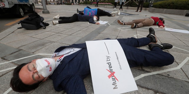 South Korean peace activists lie on a street to pay tribute to the victims of the recent protests in Burma, during a rally against Burma's military coup in Seoul, South Korea, Friday, March 26, 2021. (AP Photo/Ahn Young-joon)