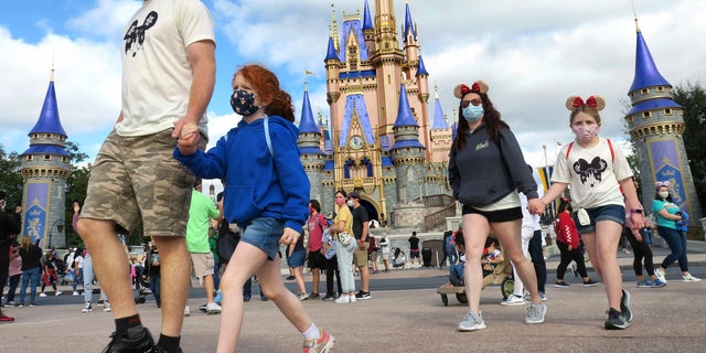 A family walks past Cinderella's Castle in the Magic Kingdom, at Walt Disney World in Lake Buena Vista, Fla. (Joe Burbank / Orlando Sentinel via AP, FILE)