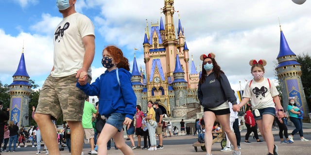 A family walks past Cinderella Castle in the Magic Kingdom, at Walt Disney World in Lake Buena Vista, Fla. (Joe Burbank/Orlando Sentinel via AP, File)