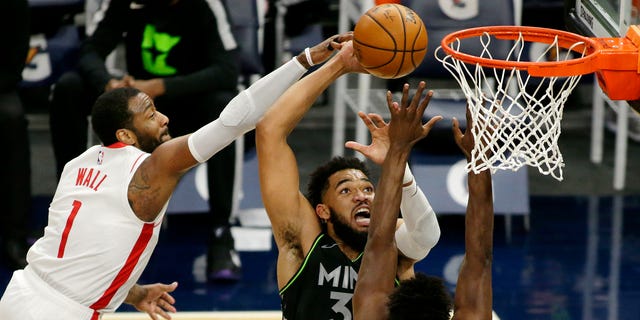 Minnesota Timberwolves center Karl-Anthony Towns (32) shoots against Houston Rockets guard John Wall (1) and forward Jae'Sean Tate (8) in the first quarter of a game March 26, 2021, in Minneapolis.