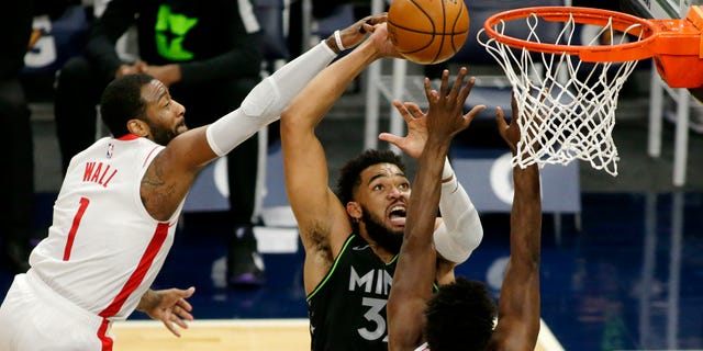 Minnesota Timberwolves center Karl-Anthony Towns (32) shoots against Houston Rockets guard John Wall (1) and forward Jae'Sean Tate (8) in the first quarter of a game March 26, 2021 in Minneapolis.