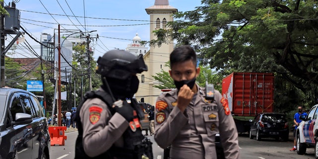 Police officers guard near a church where an explosion went off in Makassar, South Sulawesi, Indonesia, Sunday, March 28, 2021. (AP Photo/Yusuf Wahil)