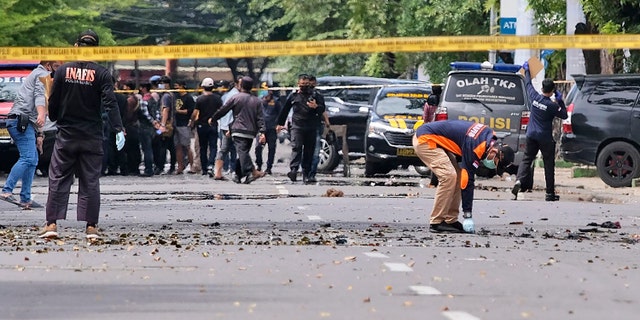 Police officers inspect the area near a church where an explosion went off in Makassar, South Sulawesi, Indonesia, Sunday, March 28, 2021. A suicide bomber blew himself up outside a packed Roman Catholic cathedral on Indonesia's Sulawesi island during a Palm Sunday Mass, wounding a number of people, police said. (AP Photo/Masyudi S. Firmansyah)