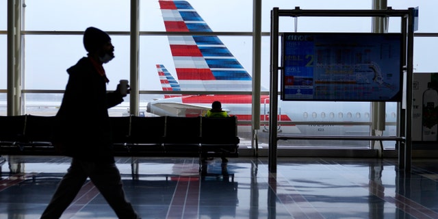 An American Airlines jet sits parked at a gate as light snow falls at Ronald Reagan Washington National Airport, Tuesday, Feb. 2, 2021. (AP Photo/Patrick Semansky)