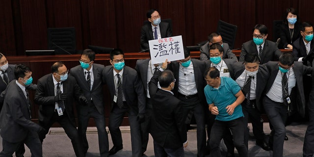 Pro-democracy lawmaker Wu Chi-wai, right in a polo shirt, scuffles with security guards during a Legislative Council's House Committee meeting in Hong Kong on May 18, 2020. (AP Photo/Vincent Yu, File)