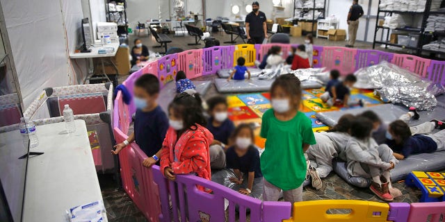 Young unaccompanied migrants, from ages 3 to 9, watch television inside a playpen at the U.S. Customs and Border Protection facility. (AP Photo/Dario Lopez-Mills, Pool)