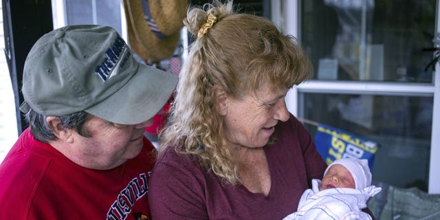 Barbara Higgins holds her son, Jack, as her husband Kenny Banzhoff looks on Wednesday, March 24, 2021 in Concord, N.H. Higgins who lost her 13-year-old daughter to a brain tumor in 2016 has given birth to a son at age 57. Barbara Higgins, and her husband, Kenny Banzhoff, of Concord, have been dealing with grief over the death of their daughter, Molly. (Geoff Forester/The Concord Monitor via AP)