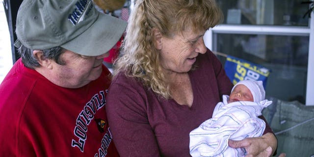 Barbara Higgins holds her son, Jack, as her husband Kenny Banzhoff looks on Wednesday, March 24, 2021 in Concord, N.H. Higgins who lost her 13-year-old daughter to a brain tumor in 2016 has given birth to a son at age 57. Barbara Higgins, and her husband, Kenny Banzhoff, of Concord, have been dealing with grief over the death of their daughter, Molly. (Geoff Forester/The Concord Monitor via AP)