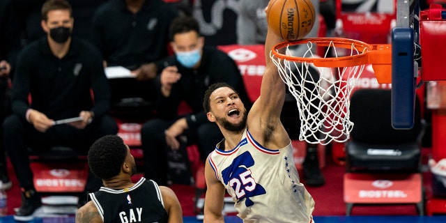 Philadelphia 76ers' Ben Simmons, right, goes up for a dunk as he passes San Antonio Spurs' Rudy Gay, left, during the first half of an NBA basketball game, Sunday, March 14, 2021, in Philadelphia.