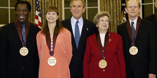 US President George W. Bush (C) stands with recipients of the National Medal of Arts in the Oval Office of the White House Nov. 12, 2003, in Washington, DC. From left are: Blues musician Buddy Guy, dancer and artistic director Suzanne Farrell, Bush, children's book author Beverly Cleary and actor-director Ron Howard. (TIM SLOAN/AFP via Getty Images)