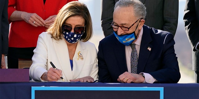 House Speaker Nancy Pelosi of Calif., signs the $1.9 trillion COVID-19 relief bill, accompanied by Senate Majority Leader Chuck Schumer of N.Y., during an enrollment ceremony on Capitol Hill, Wednesday, March 10, 2021, in Washington. (AP Photo/Alex Brandon)