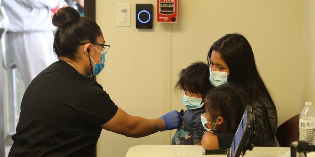 Une famille de migrants transportée de la vallée du Rio Grande au centre de traitement central de la patrouille frontalière du secteur d'El Paso, au Texas, est soumise à un examen médical initial par un entrepreneur qui supervise la santé et le bien-être des unités familiales et des mineurs non accompagnés.  (Photo: Patrouille frontalière américaine)