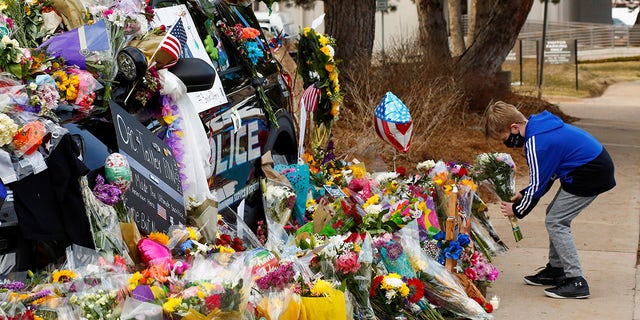 A child lays flowers near the police car of officer Eric Talley who died Monday responding to a call where a gunman opened fire on people in a King Soopers grocery store in Boulder, Colorado, U.S. March 24, 2021. 