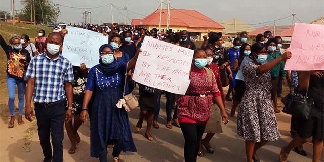 Nurses and supporters in Owo, Nigeria, participate in a march on Feb. 7, 2021, demanding the Federal Medical Centre in Owo provide security for its staff after two nurses were were attacked by the family of a deceased COVID-19 patient.  (Tochukwu Q.O. via AP)
