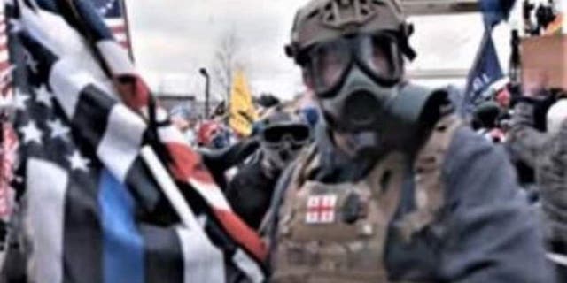 A man identified by the FBI as Jeffrey McKellop is seen holding a "thin blue line" flag during the Capitol riot. McKellop has been charged with assaulting police officers, including throwing a flagpole at one.
