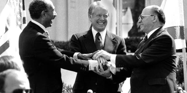 Egyptian President Anwar Sadat, left, U.S. President Jimmy Carter, center, and Israeli Prime Minister Menachem Begin clasp hands on the north lawn of the White House after signing the peace treaty between Egypt and Israel on March 26, 1979. (AP Photo/ Bob Daugherty)