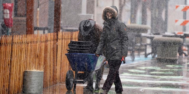 Workers use a wheelbarrell to collect chairs from an outdoor dining area in Larimer Square as a snowstorm sweeps over the intermountain West Saturday, March 13, 2021, in Denver. Forecasters were predicting up to three feet of snow from the lumbering storm, which started slowly around the noon hour Saturday. (AP Photo/David Zalubowski)
