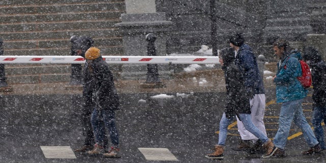 Pedestrians fight blowing snow as they move eastbound along Colfax Avenue as a snowstorm sweeps over the intermountain West Saturday, March 13, 2021, in Denver. (AP Photo/David Zalubowski)