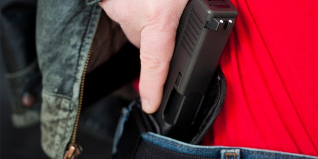 Man's hand on hip-holstered gun