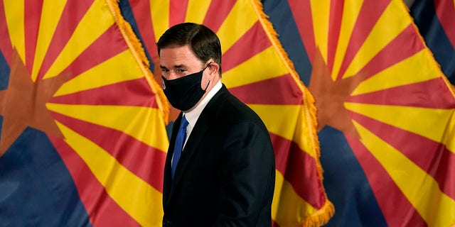 FILE - In this Dec. 2, 2020, file photo, Arizona Republican Gov. Doug Ducey arrives for a news conference to talk about the latest Arizona COVID-19 information in Phoenix. Ducey is prohibiting government mask mandates and allowing bars and nightclubs shuttered for months to open their doors without restrictions. Ducey's move Thursday, March 25, 2021, leaves in place few of the restrictions he implemented to curb the spread of the coronavirus. (AP Photo/Ross D. Franklin, Pool, File)