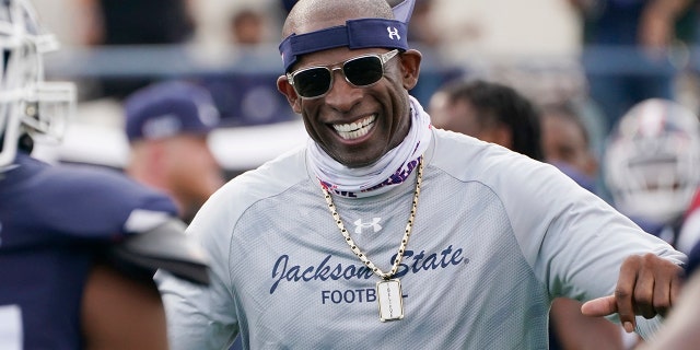 Jackson State football coach Deion Sanders smiles as he greets his defensive squad after they had recovered a Mississippi Valley State fumble for a touchdown during the second half of an NCAA college football game, Sunday, March 14, 2021, in Jackson, Miss.