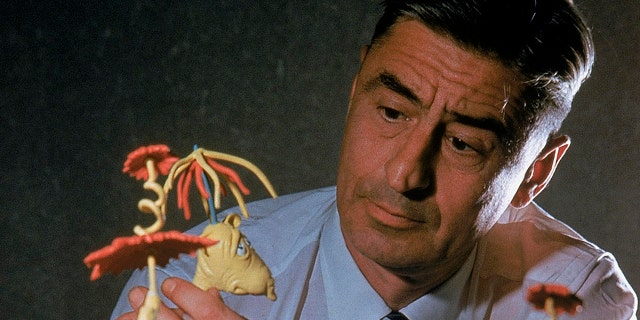 1959: Author/illustrator Theodor Seuss Geisel posing w. models of characters he has created.