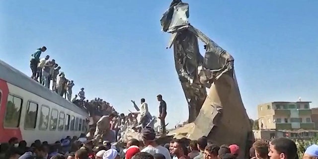 This screengrab provided by AFPTV ahows people gathered around the wreckage of two trains that collided in the Tahta district of Sohag province, some 285 miles south of Cairo, killing at least 32 people and injuring scores of others, on March 26, 2021.