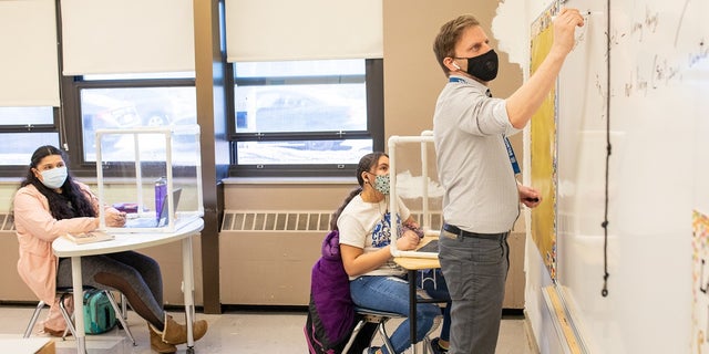 A teacher instructs students in a social distanced classroom.