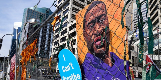 A picture of George Floyd hangs on a fence outside the Hennepin County Government Center, Tuesday, March 30, 2021, in Minneapolis where the trial for former Minneapolis police officer Derek Chauvin continues. (AP Photo/Jim Mone)