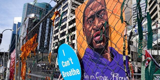 A picture of George Floyd hangs on a fence outside the Hennepin County Government Center, Tuesday, March 30, 2021, in Minneapolis where the trial for former Minneapolis police officer Derek Chauvin continues. (AP Photo/Jim Mone)