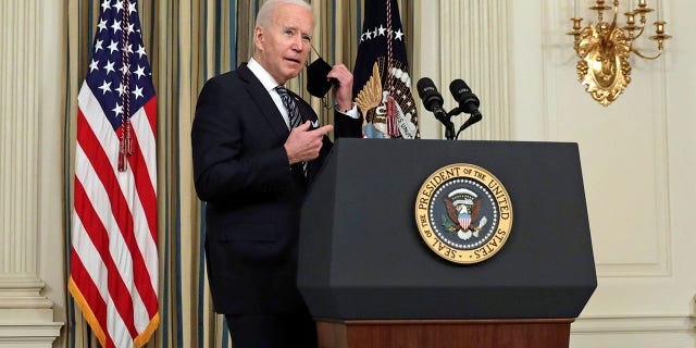 U.S. President Joe Biden removes a protective mask before delivering remarks on the implementation of the American Rescue Plan in the State Dining Room of the White House in Washington, D.C., U.S., on Monday, March 15, 2021. (Photographer: Yuri Gripas/Abaca/Bloomberg via Getty Images)