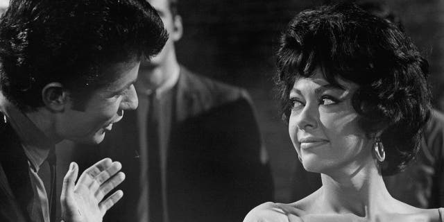 Rita Moreno listens while George Chakiris speaks with her in a scene from the film 'West Side Story'.