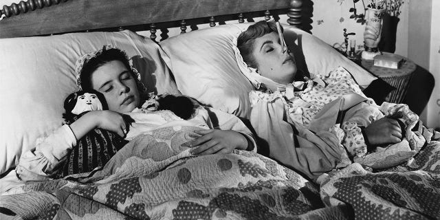 Margaret O'Brien (left) and Elizabeth Taylor forget their troubles in dreams in this scene from MGM's Technicolor production of Louisa May Alcott's 'Little Women'. The clothespin on Taylor's nose is a beauty secret of the time - purported to give the wearer a seemingly slimmer nose. The movie was produced and directed by Mervyn LeRoy.