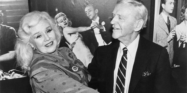 Fred Astaire and Ginger Rogers take a turn around the dance floor June 23 during luncheon celebrating RKO General's donation of RKO Radio Pictures' archives to the University of California, Los Angeles. A poster from one of their films forms the backdrop.