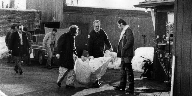 Investigators carry the remains of a body found beneath the garage floor of the home of John Wayne Gacy on December 22, 1978, in Chicago.