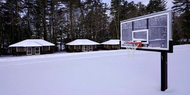 Snow covers a basketball court at Camp Fernwood, a summer camp for girls, Saturday, Feb. 20, 2021, in Poland, Maine. (AP Photo/Robert F. Bukaty)