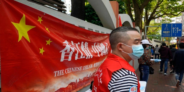 A pro-China staff member stands at a stall to support a proposal to draft changes of election rules for Hong Kong on a downtown street in Hong Kong. (AP)