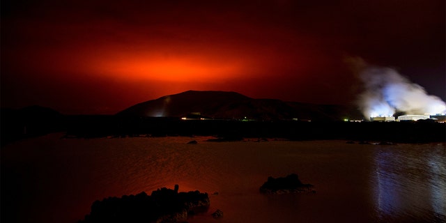 TOPSHOT - The red shimmer from magma flowing out from the erupting Fagradalsfjall volcano behind the landmark Blue Lagoon, some 45 km west of the Icelandic capital Reykjavik, on March 19, 2021. - A volcano erupted in Iceland on Friday some 40 kilometres (25 miles) from the capital Reykjavik, the Icelandic Meteorological Office said, as a red cloud lit up the night sky and a no-fly zone was established in the area. (Photo by Halldor KOLBEINS / AFP) (Photo by HALLDOR KOLBEINS/AFP via Getty Images)