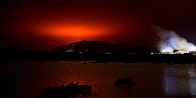 TOPSHOT - The red shimmer from magma flowing out from the erupting Fagradalsfjall volcano behind the landmark Blue Lagoon, some 45 km west of the Icelandic capital Reykjavik, on March 19, 2021. - A volcano erupted in Iceland on Friday some 40 kilometres (25 miles) from the capital Reykjavik, the Icelandic Meteorological Office said, as a red cloud lit up the night sky and a no-fly zone was established in the area. (Photo by Halldor KOLBEINS / AFP) (Photo by HALLDOR KOLBEINS/AFP via Getty Images)