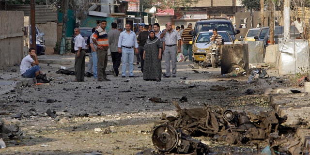 File - In this Monday Nov. 1, 2010 file photo, Iraqis inspect the scene of a car bomb attack in front of a Our Lady of Salvation Church in Baghdad, in Baghdad, Iraq. (AP Photo/Khalid Mohammed, File)