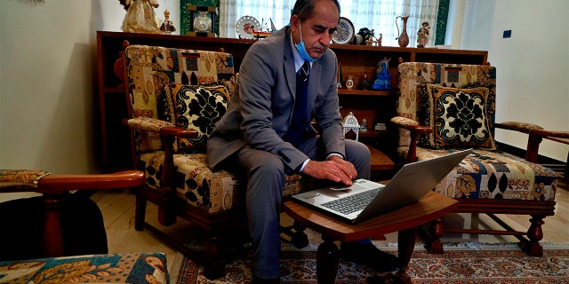 Louis Clemis reviews photos of the storming of the church on his laptop during an interview with The Associated Press in Baghdad, Iraq, Sunday, Feb. 17, 2021. (AP Photo/Hadi Mizban)