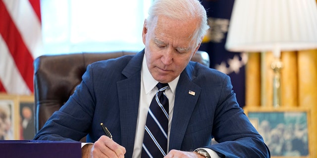 President Joe Biden signs the American Rescue Plan, a coronavirus relief package, in the Oval Office of the White House, 星期四, 游行 11, 2021, 在华盛顿.