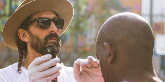 Celebrity men's groomer Jason Schneidman giving haircuts on the streets of Venice, California.