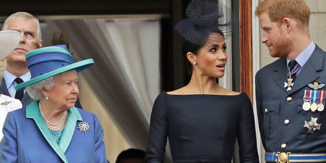 Königin Elizabeth, Megan Markle und Prinz Harry stehen 2018 auf einem Balkon, um zu sehen, wie das Flugzeug der Royal Air Force über den Buckingham Palace fliegt.