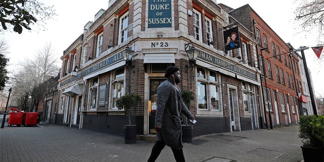 A man walks past the Duke of Sussex pub with a sign depicting the image of Britain's Prince Harry and his wife Meghan, near Waterloo station, London, Tuesday March 9, 2021. (AP Photo/Frank Augstein)