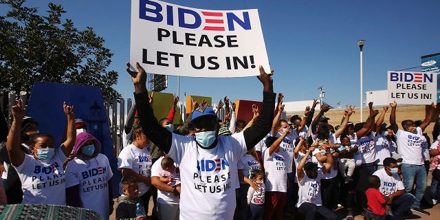 Migrants from Central America and elsewhere, hoping to cross and request asylum in the U.S., hold banners and shout slogans to President Biden. (REUTERS/Jorge Duenes)