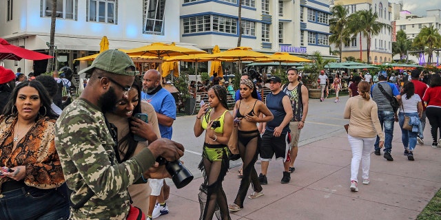 A pesar del coronavirus, las vacaciones de primavera regresan a South Beach y caminan por Ocean Drive, que está cerrada al tráfico el jueves 12 de marzo de 2021. Los funcionarios de Miami Beach están imponiendo un toque de queda de emergencia de 8 p. -controlar las multitudes de las vacaciones de primavera abarrotaron las playas, destrozaron algunas propiedades de restaurantes y se pelearon en las calles. Se les dice a los turistas y huéspedes del hotel que permanezcan en el interior durante las horas del toque de queda. (Al Díaz/Miami Herald vía AP)