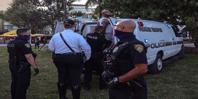 An unidentified man is detained and later arrested on Sunday in Miami Beach. (AP/Miami Herald)