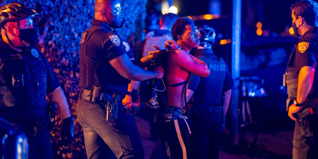 A man is arrested while out a few hours past curfew in Miami Beach, Fla., on Sunday, March 21, 2021. Miami Beach commissioners voted unanimously Sunday to extend the 8 p.m. to 6 a.m. curfew Thursday through Sunday in the South Beach entertainment district until at least April 12, effectively shutting down a spring break hot spot in one of the few states fully open during the pandemic. (Daniel A. Varela/Miami Herald via AP)